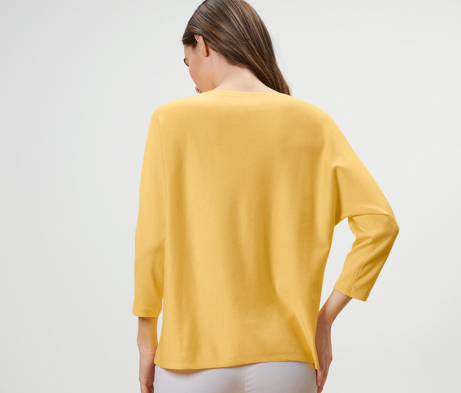 Frau trägt einen gelben Feinstrickpullover.