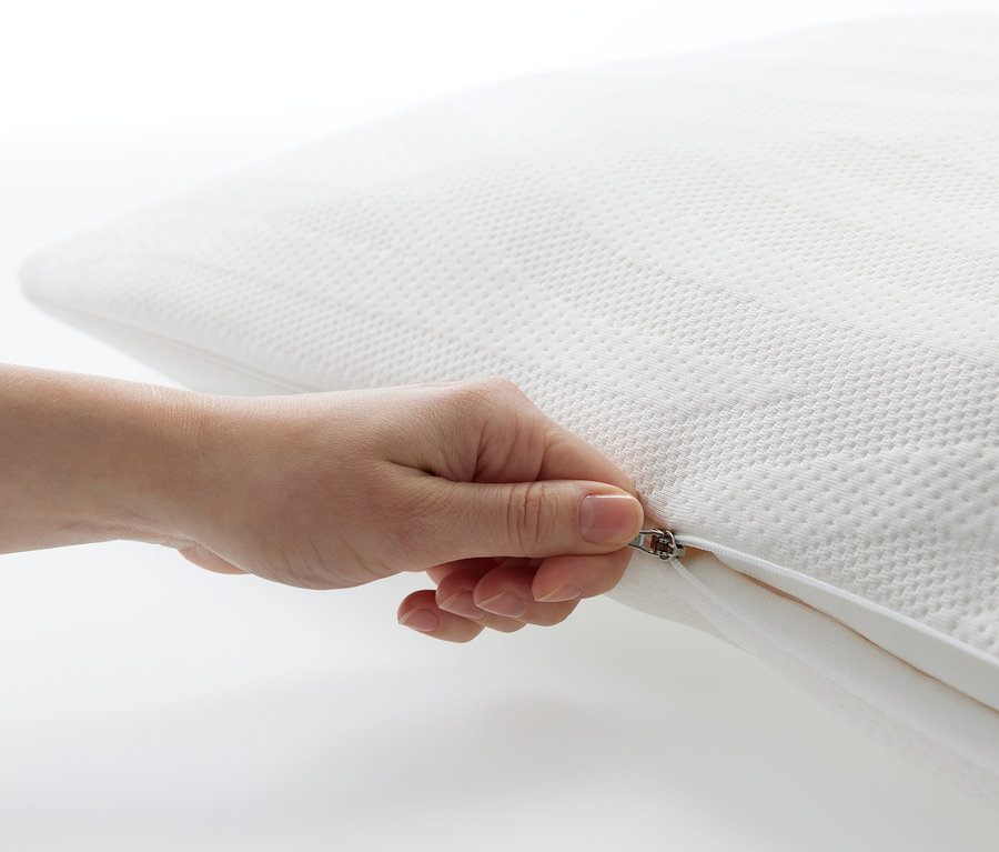 Eine Hand öffnet den Reißverschluss eines weißen TEMPUR® Comfort Pureclean Schlafkissens.