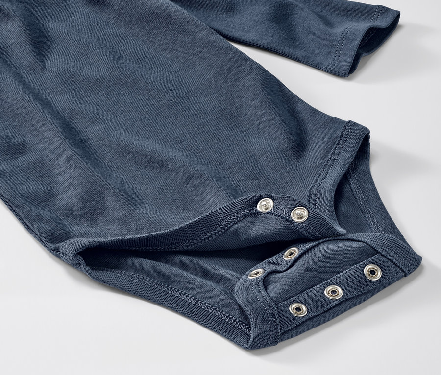 Detailansicht eines blauen Baby-Bodys mit Mitwachsfunktion und langen Ärmeln, der mit Druckknöpfen geschlossen wird.