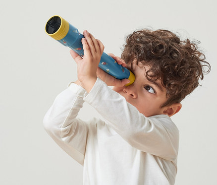 Junge schaut durch ein Spiel-Fernrohr.