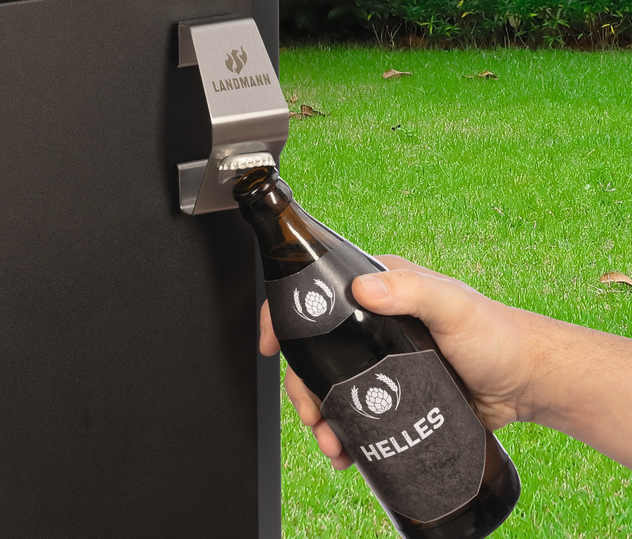 Eine Hand öffnet eine braune Bierflasche an einem Landmann magnetischen Zubehörteil an der Seite eines Grills.