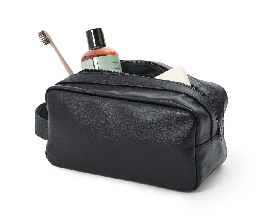 Eine schwarze Kulturtasche mit einer braunen Flasche, einer Zahnbürste und Seife.
