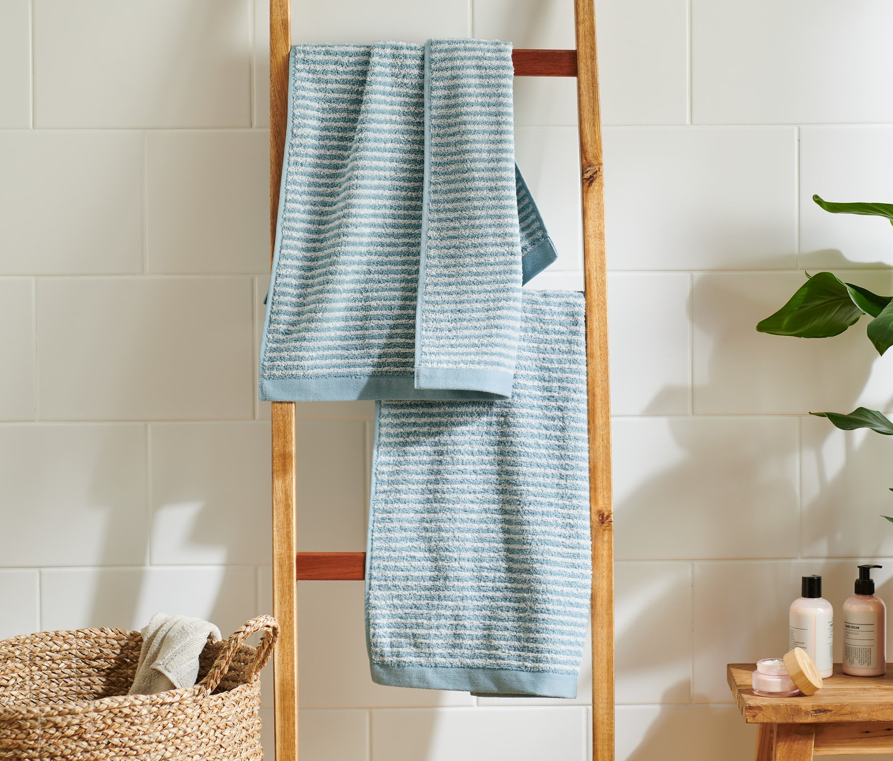 Zwei hochwertige hellblaue und blaue Handtücher hängen auf einer Holzleiter im Badezimmer.