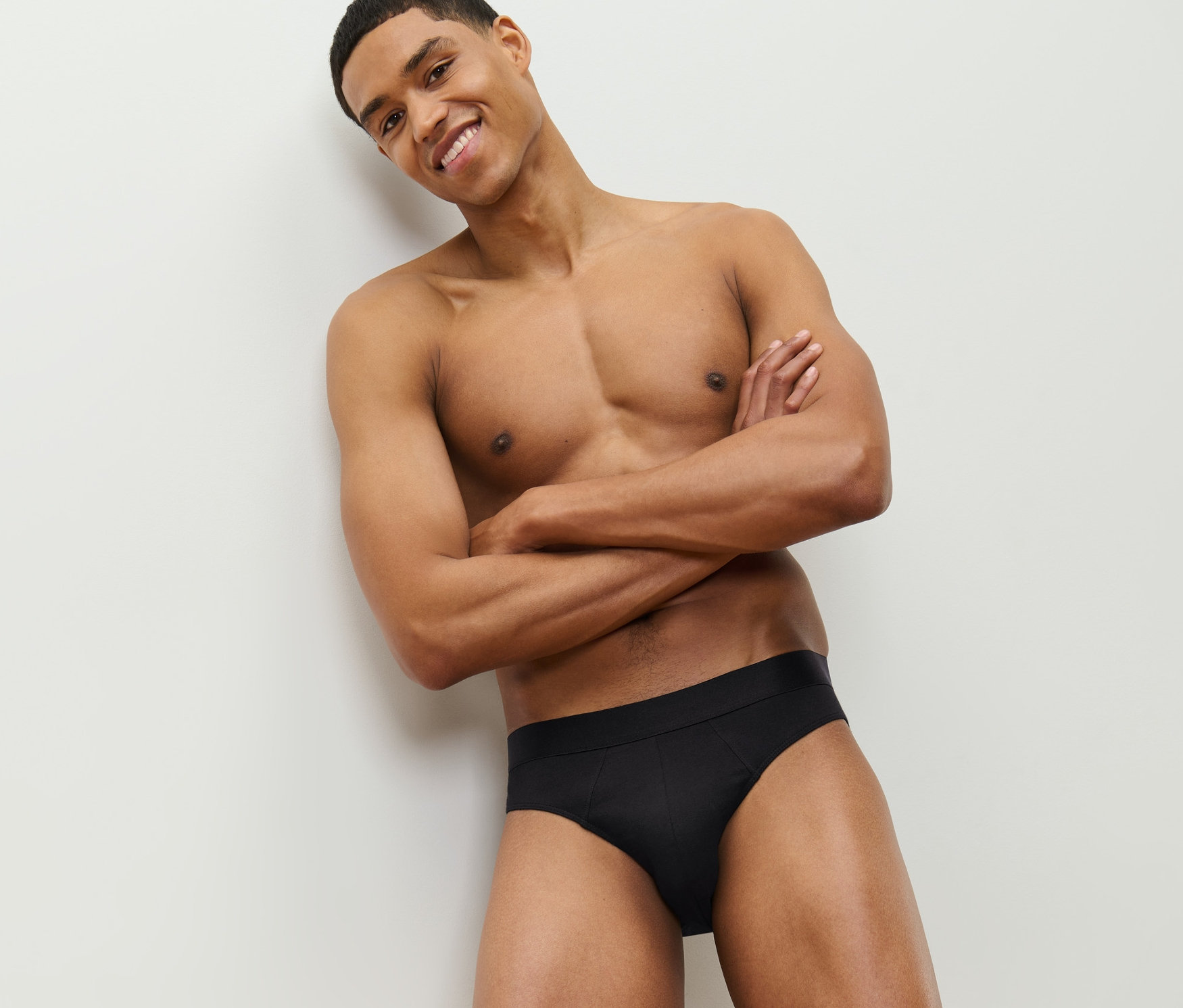 Lächelnder Mann posiert mit verschränkten Armen und trägt 4 Slips in Schwarz.