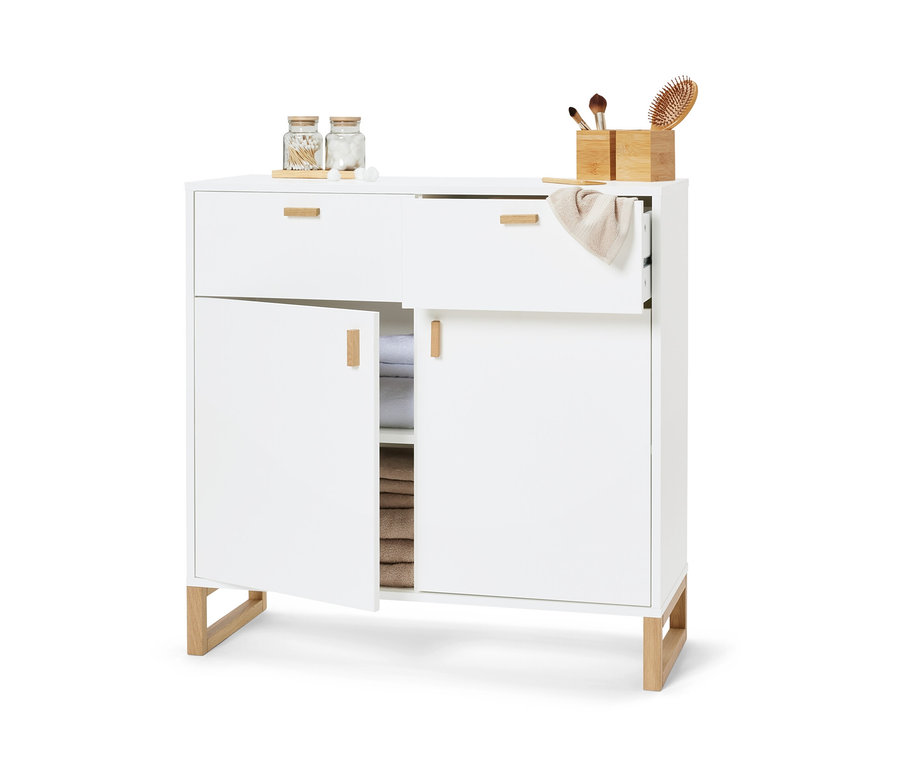 Weißes Sideboard mit 2 Schubladen und 2 Türen, wobei eine Tür geöffnet ist und das Innere mit Handtüchern gefüllt ist.