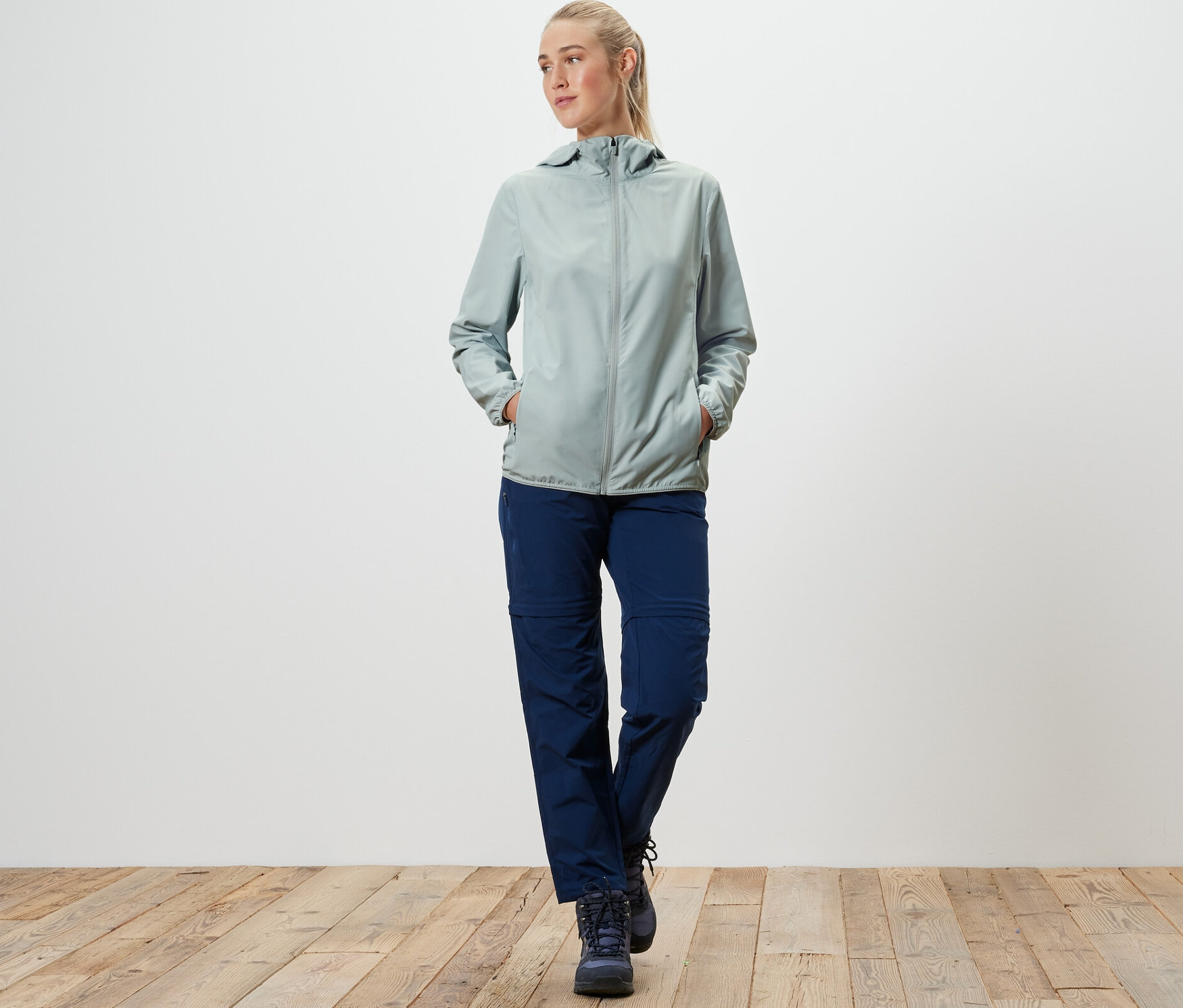 Frau geht und trägt eine graue, packbare Funktionsjacke.