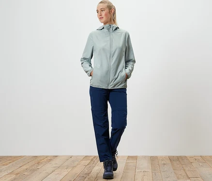 Frau geht und trägt eine graue, packbare Funktionsjacke.