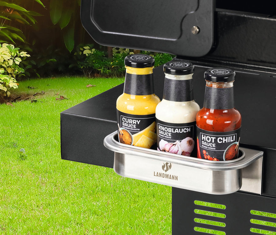 Landmann magnetisches Zubehör ist am Grill befestigt, darauf stehen drei Saucenflaschen: Curry, Knoblauch und Chili.
