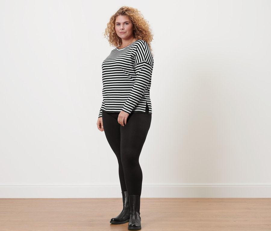 Frau trägt ein gestreiftes Langarmshirt, schwarze Leggings und schwarze Stiefel.