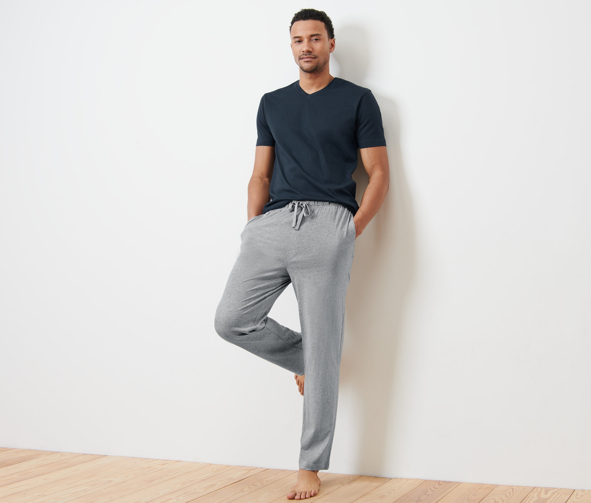 Mann an eine Wand gelehnt trägt einen Pyjama.