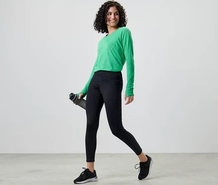 Frau mit grünem Shirt und Thermotight hält eine Wasserflasche.