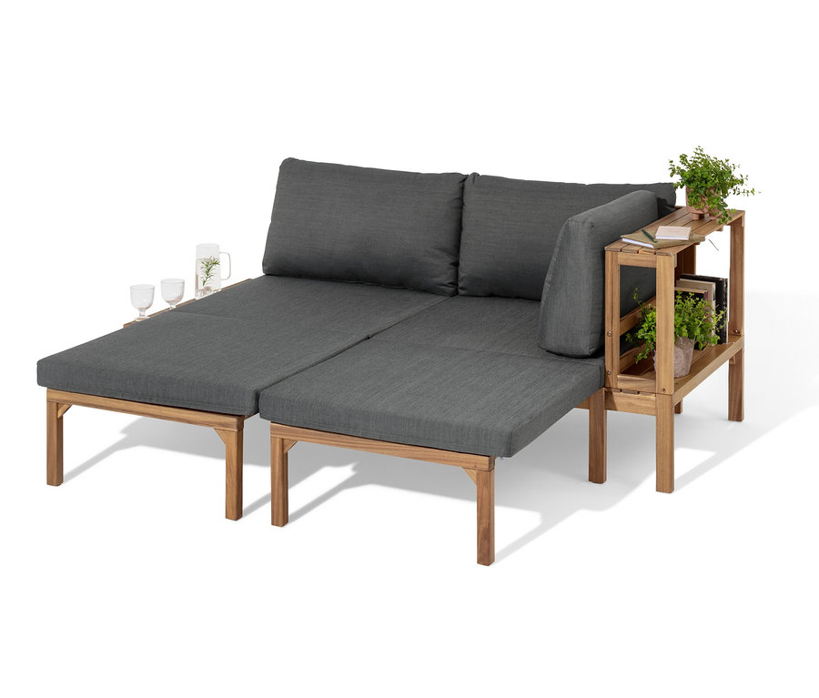 Flexible Lounge-Ecke »Tinus« mit ausziehbaren Fußlehnen und Holzregal. Auf der Lounge-Ecke stehen Gläser mit Getränk.