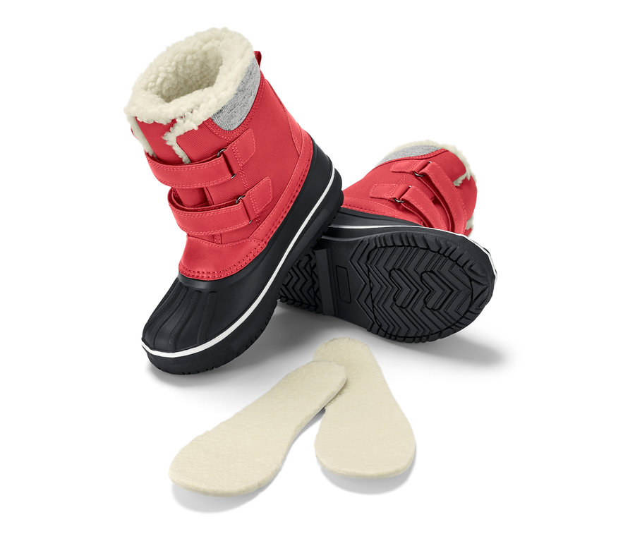 Ein roter Kinder-Allwetterstiefel liegt auf der Seite, daneben liegen Einlegesohlen.