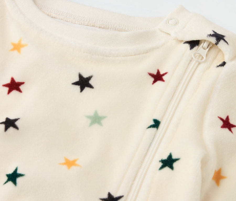 Detailansicht eines Baby-Nicki-Schlafanzugs mit Reißverschluss und Sternen.