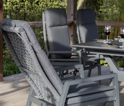 Graues deVries Dining-Set mit Seiloptik auf einer Terrasse; auf dem Tisch stehen Weingläser und Snacks.