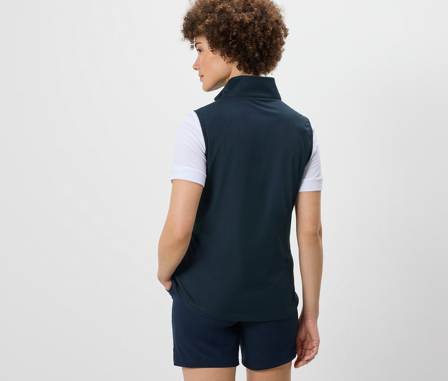 Rückansicht einer Frau mit Afro, die eine Softshellweste und Shorts trägt.