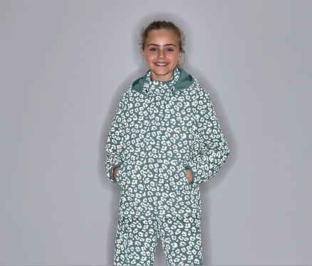 Mädchen posiert in einer Thermo-Regenjacke mit reflektierenden Elementen und Leopardenmuster.