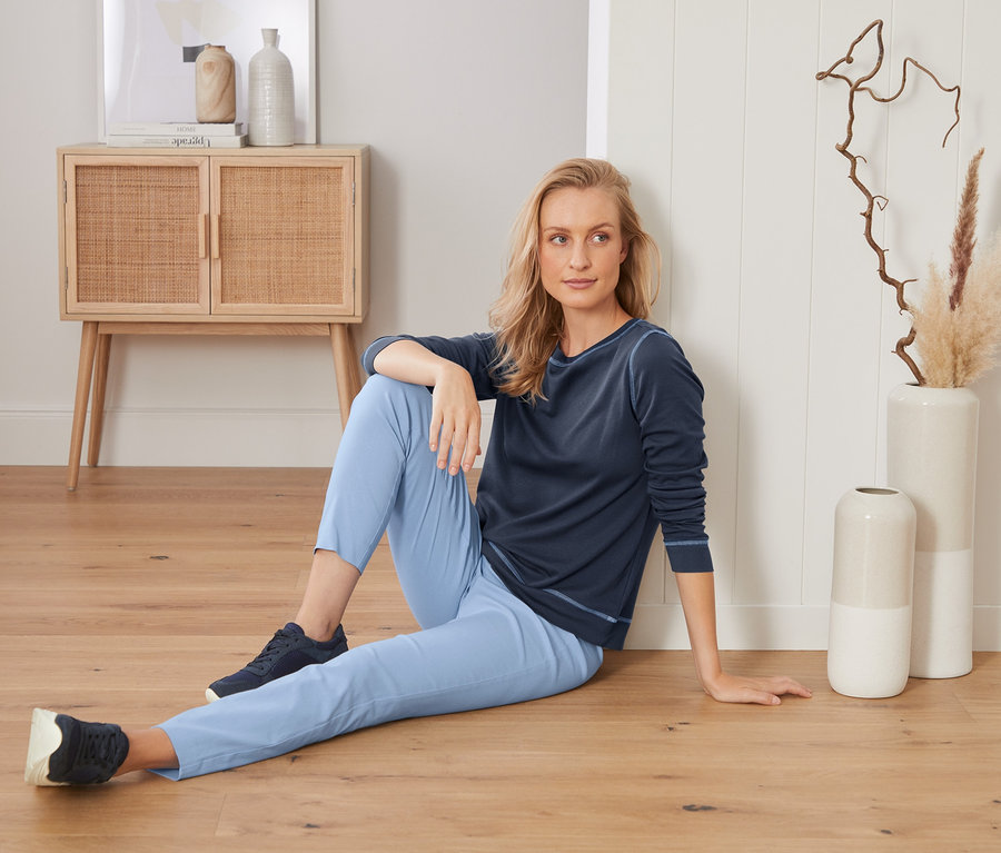 Frau sitzt auf dem Boden und trägt eine Stretchhose.