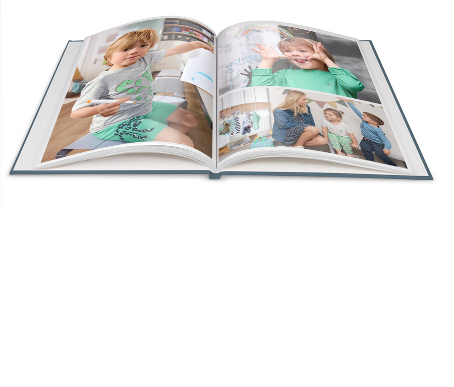 Ein geöffnetes Buch zeigt Fotos von einem zeichnenden Jungen und einer Frau mit Kindern.