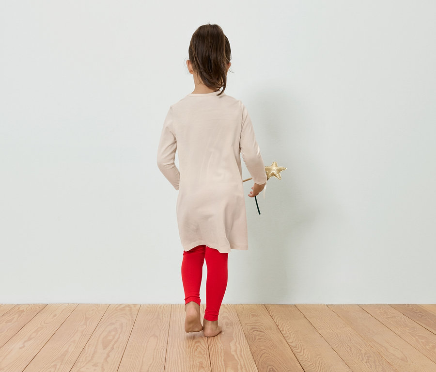 Mädchen in Kleid und Leggings hält einen Stern in der Hand und steht mit dem Rücken zur Kamera.