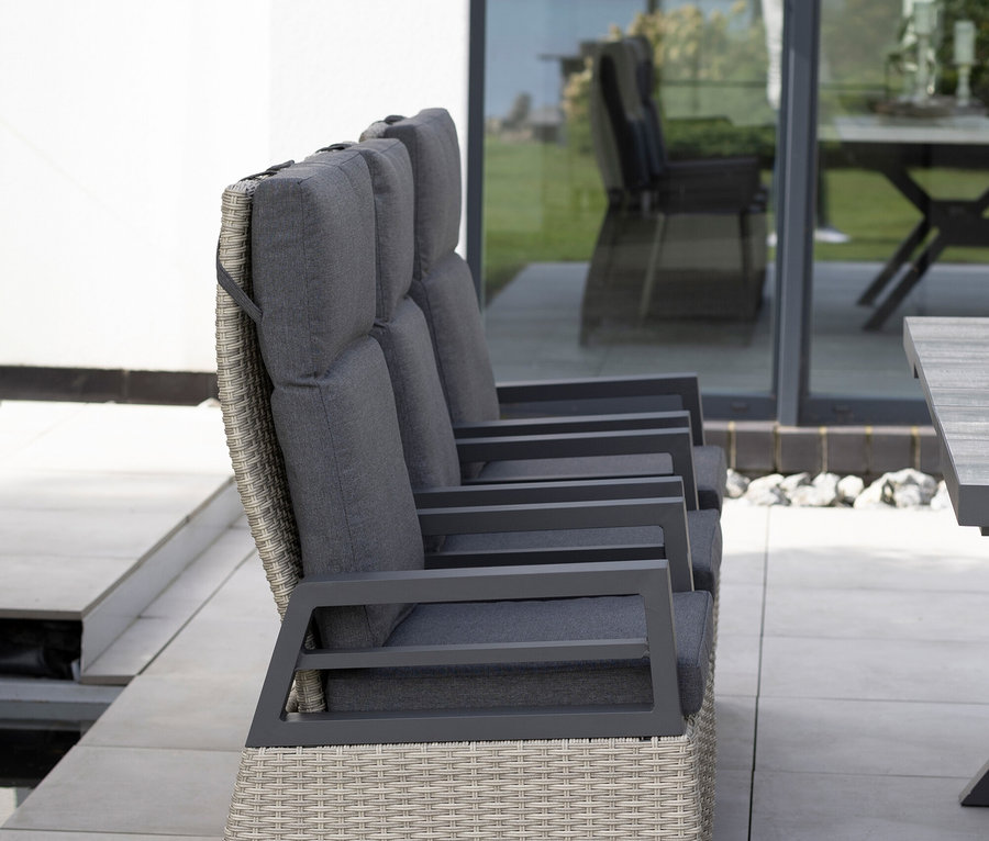 Ein Dreisitzer-Sofa mit grauen Kissen steht auf einer Terrasse neben einem Fenster.