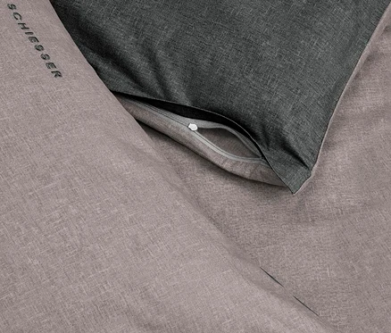 SCHIESSER Renforcé-Bettwäscheset „Doubleface“ in Grau/Schwarz. Ein hellgrauer Bettbezug mit Logo und ein teilweise geöffneter dunkelgrauer Kissenbezug.