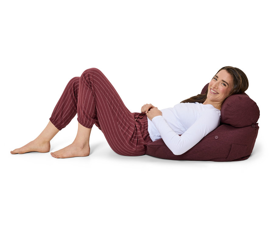 Eine Frau liegt auf einem Sitzsack in gestreifter Hose und lächelt.