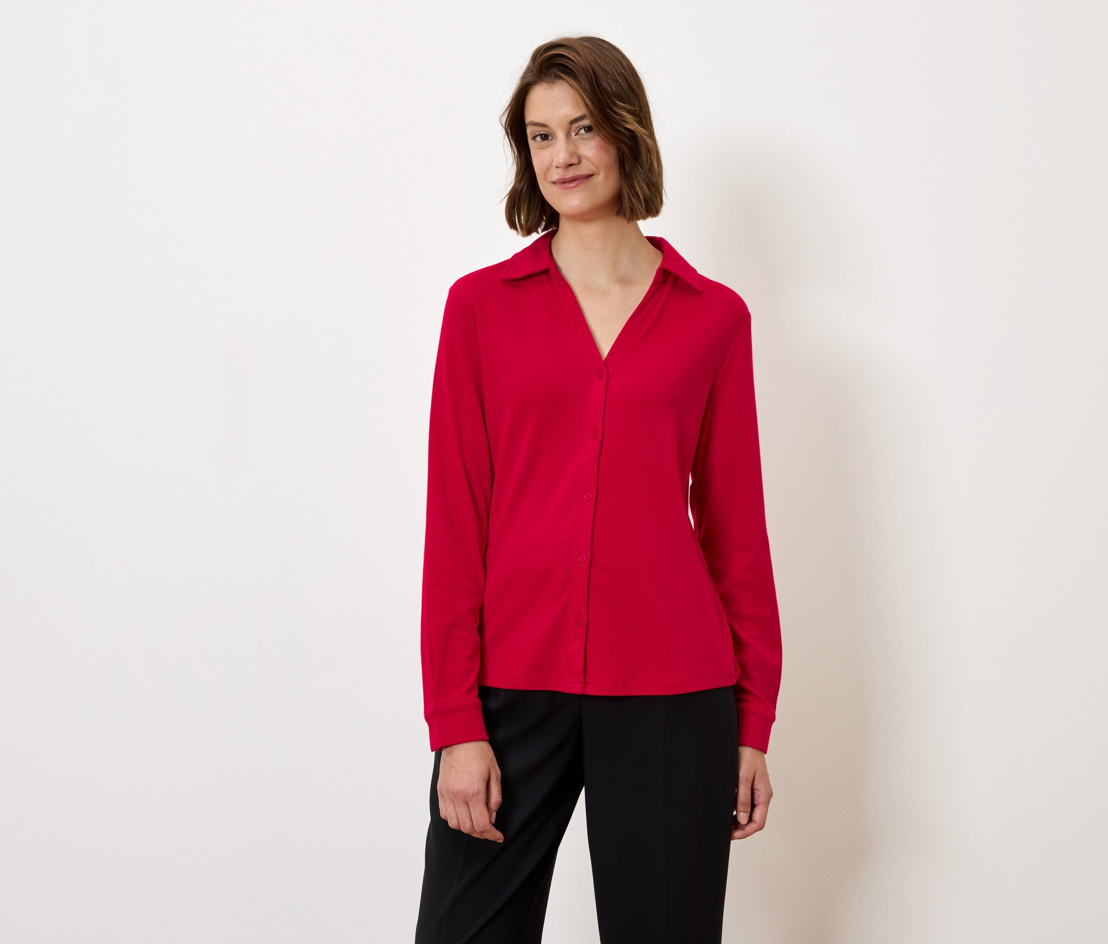 Frau trägt eine rote Bluse und schwarze Hose.