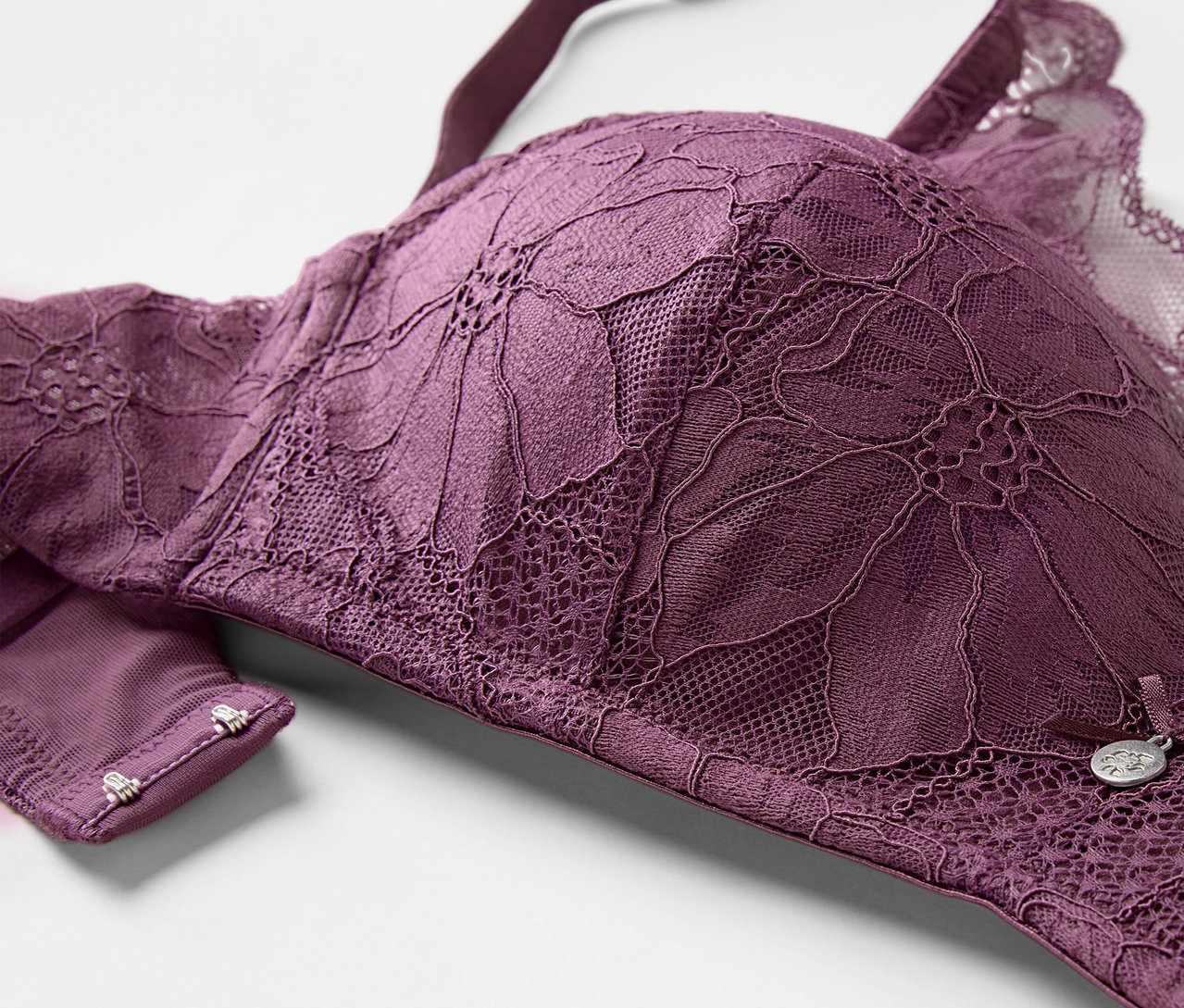 Detailansicht eines auberginefarbenen Softschalen-BHs mit Blumenspitze.