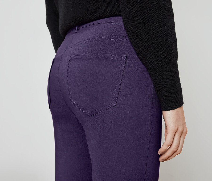 Detailansicht der Rückseite einer Person in violetten Hosen und schwarzem Pullover.