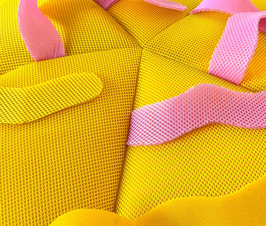 Nahaufnahme eines gelben Netzstoffs mit rosa Akzenten.