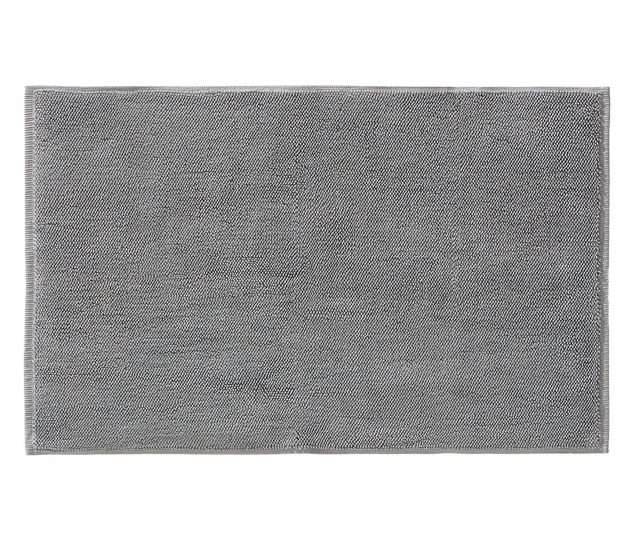 Ein grauer Badteppich liegt flach auf einer ebenen Fläche.
