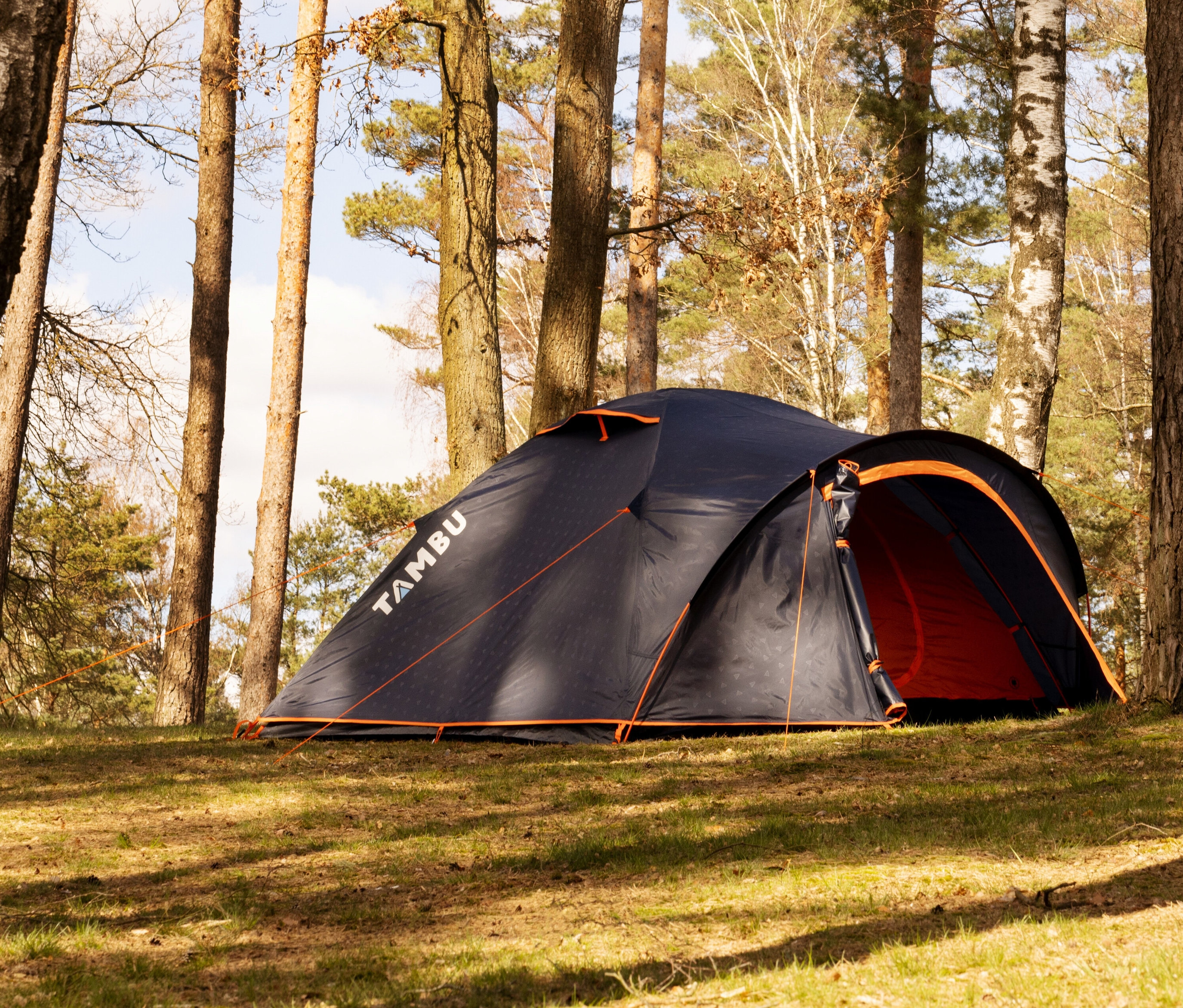 Auf einer Wiese zwischen Bäumen steht ein Tambu »HAIKA 4« 4-Personen-Kuppelzelt.
