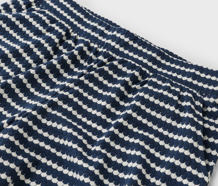 Nahaufnahme eines Teils einer marineblauen Hose mit weißen geometrischen Mustern.