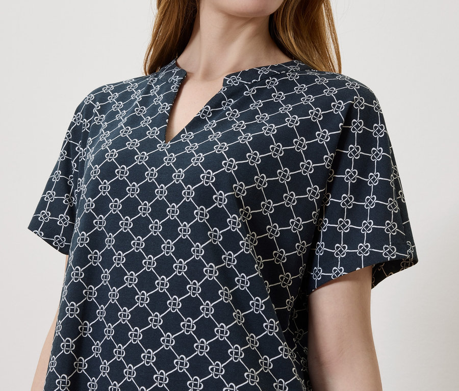 Eine Frau trägt eine dunkelblaue Bluse mit einem weißen Muster.