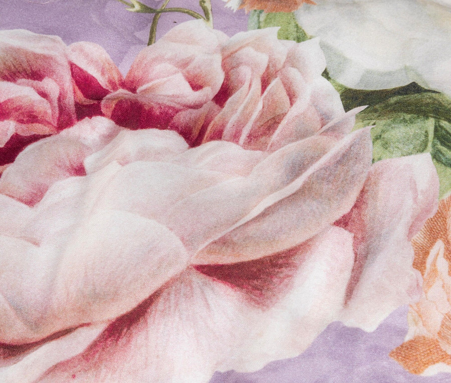 Nahaufnahme eines lila Stoffes mit rosa- und weißen Rosenmuster.