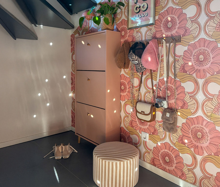 Aprikosenfarbener Schuhschrank »Bjarne« mit drei Klappen neben gestreiftem Hocker und Schuhen.