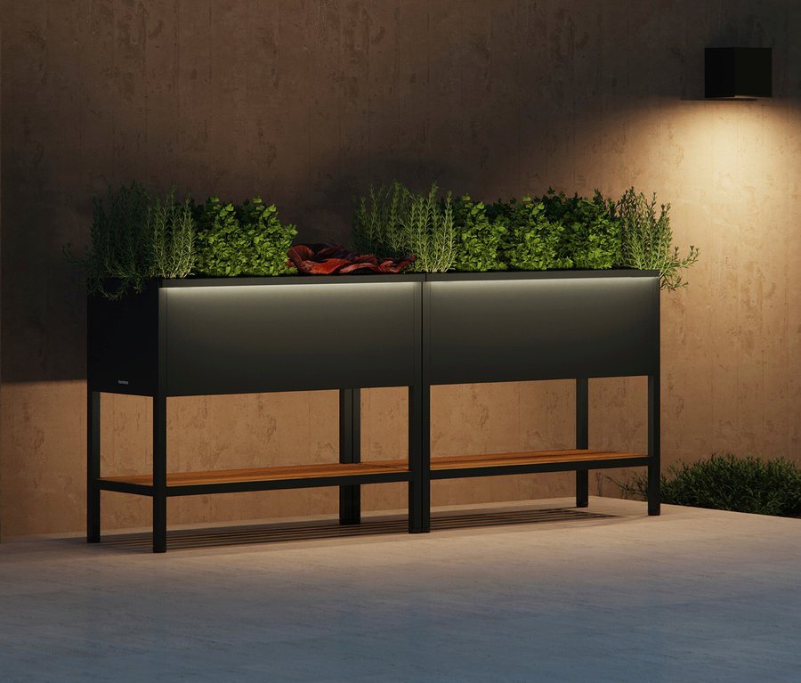 Zwei erhöhte, schwarze Pflanzkästen mit Holzregal, bepflanzt mit Grünpflanzen und Kräutern, beleuchtet.