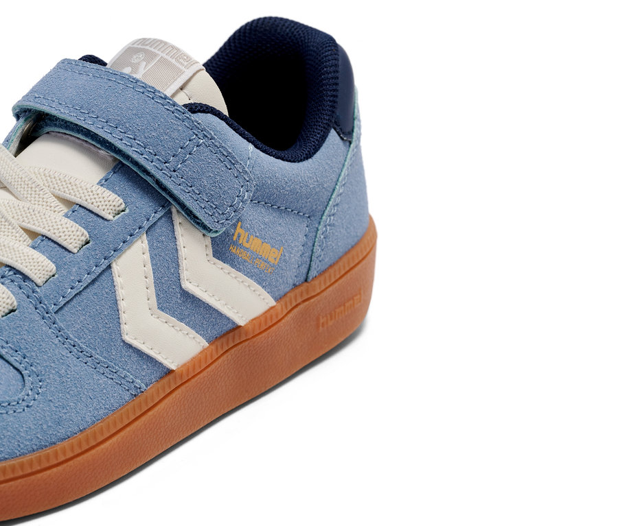 Nahaufnahme eines einzelnen hellblauen Hummel-Sneakers mit Klettverschluss und weißen Chevron-Streifen auf einer braunen Sohle.