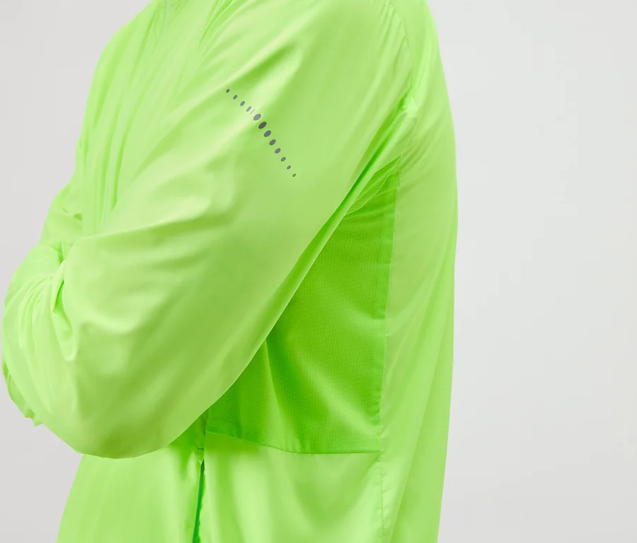 Person mit verschränkten Armen trägt eine hellgrüne Jacke mit reflektierenden Details.