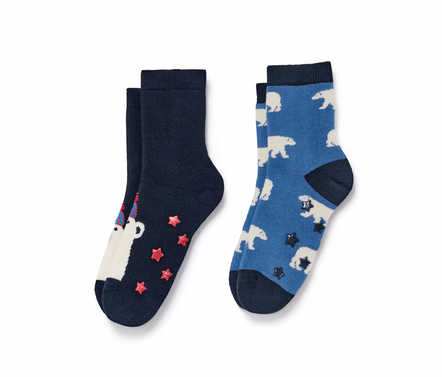 Zwei Paar Socken. Ein Paar ist marineblau mit einem weißen Bären mit Geburtstagshut und roten Sternen, das andere Paar ist blau mit weißen Eisbären und dunklen Sternen.