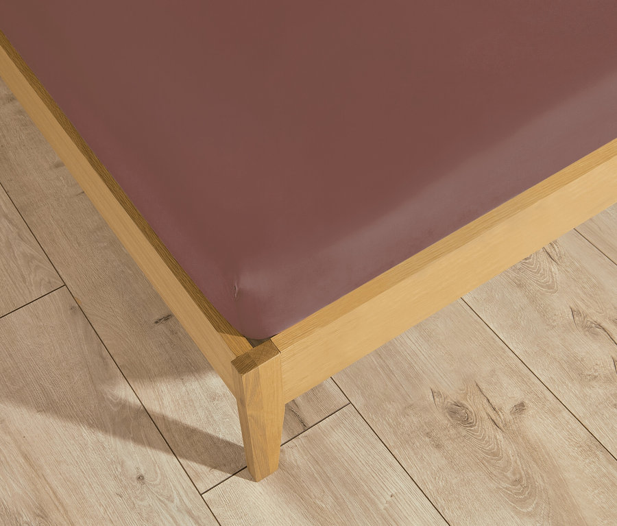 Helles Holz-Bettgestell mit einem SCHÖNER WOHNEN-Kollektion Jersey-Spannbettlaken in Mauve auf einem Holzboden.