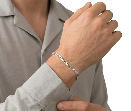 Mann trägt ein Amor 925 Silber Figaro Herren-Armband am Handgelenk und hält den Ärmel seines hellgrauen Hemdes fest.