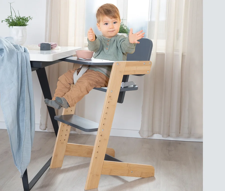 Kind sitzt im anthrazitfarbenen roba Babyhochstuhl am Tisch.