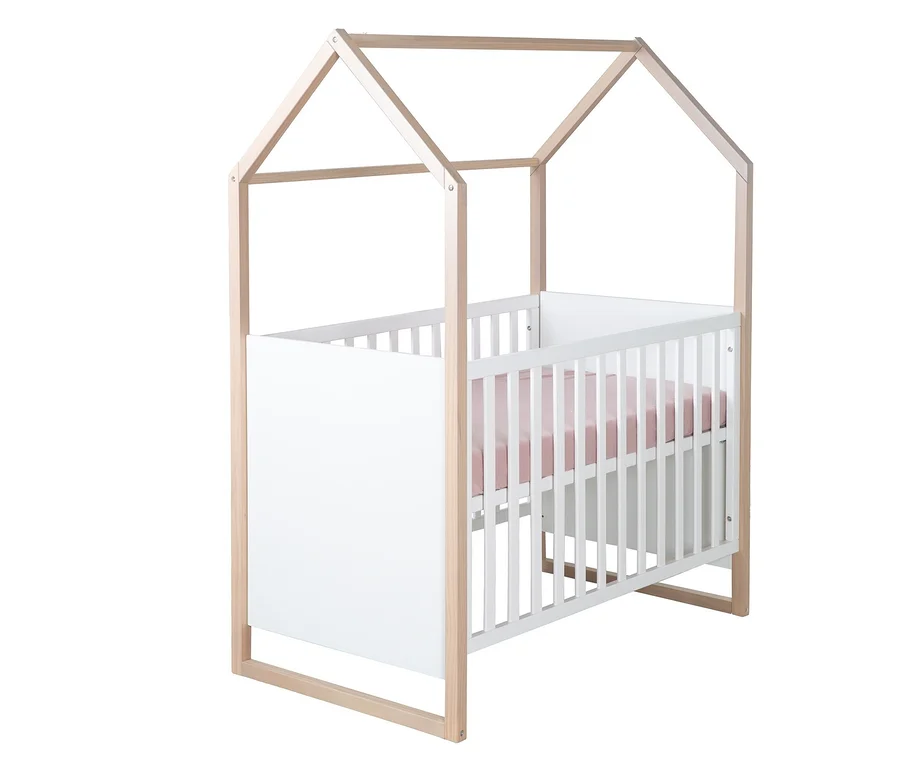 Babybett mit hellem Holzrahmen in Hausform, weißem Gitter und rosa Matratze auf weißem Hintergrund.