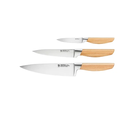 Drei Henckels by ZWILLING »Pakka« Messer mit silbernen Klingen und hellen Holzgriffen, diagonal angeordnet.