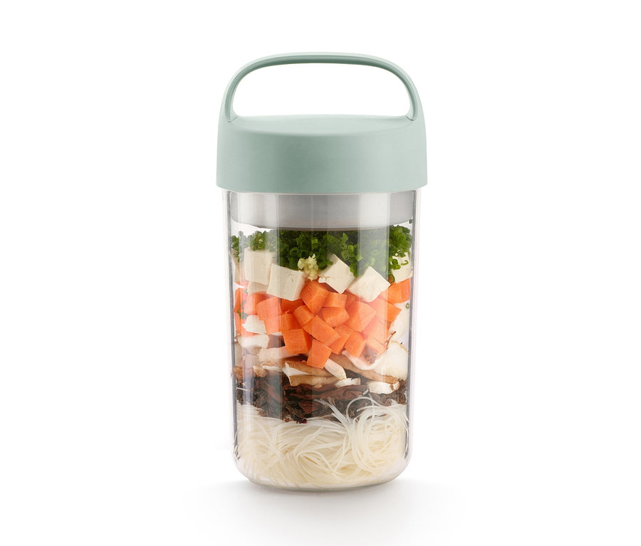 Eine To-go-Lunchbox gefüllt mit geschnittenem Gemüse, Nudeln und Pilzen.