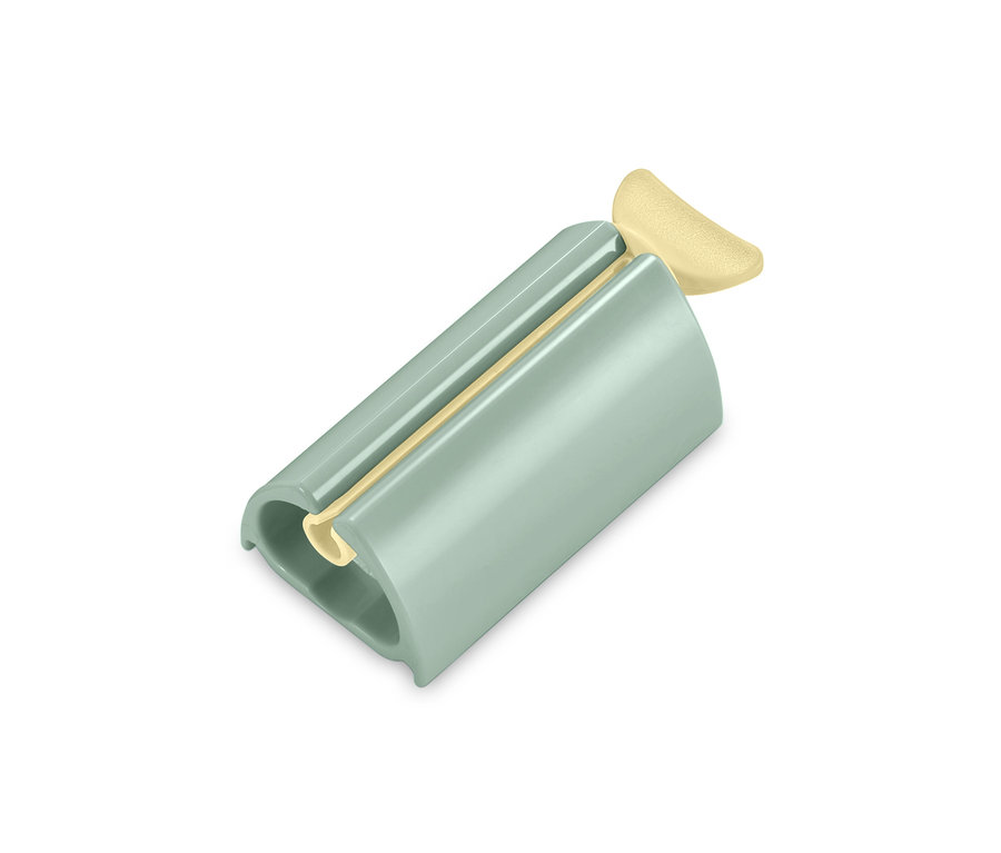 Ein grüner Tubenpresser mit einer beigen Tube.