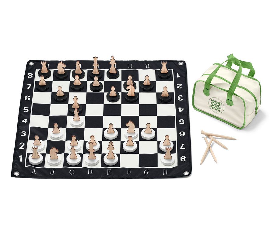 XL-Schachspiel ist auf einem schwarz-weißen Schachbrett mit Holzfiguren ausgelegt, daneben eine Tasche.