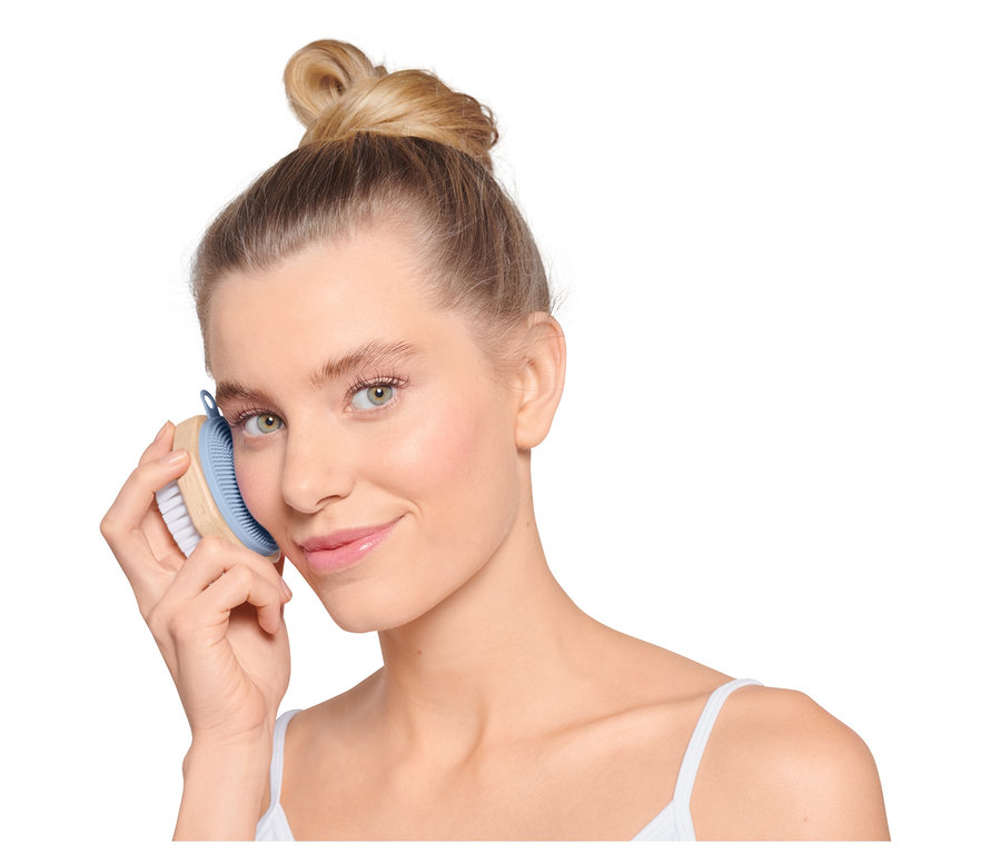 Frau benutzt eine Gesichtsreinigungsbürste.